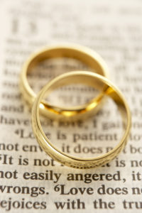 Two Wedding Rings Resting On A Bible Page